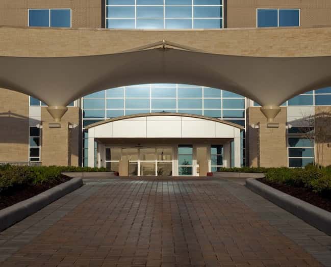 Vista nocturna de la fachada del hotel con la tensoestructura iluminada.