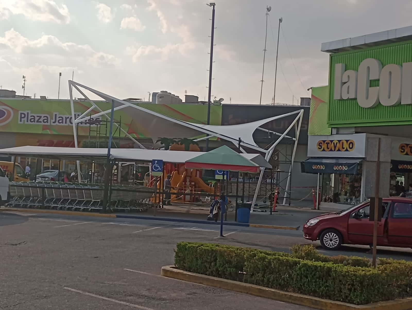 Diseño moderno de la tensoestructura integrada en el área recreativa de la plaza.
