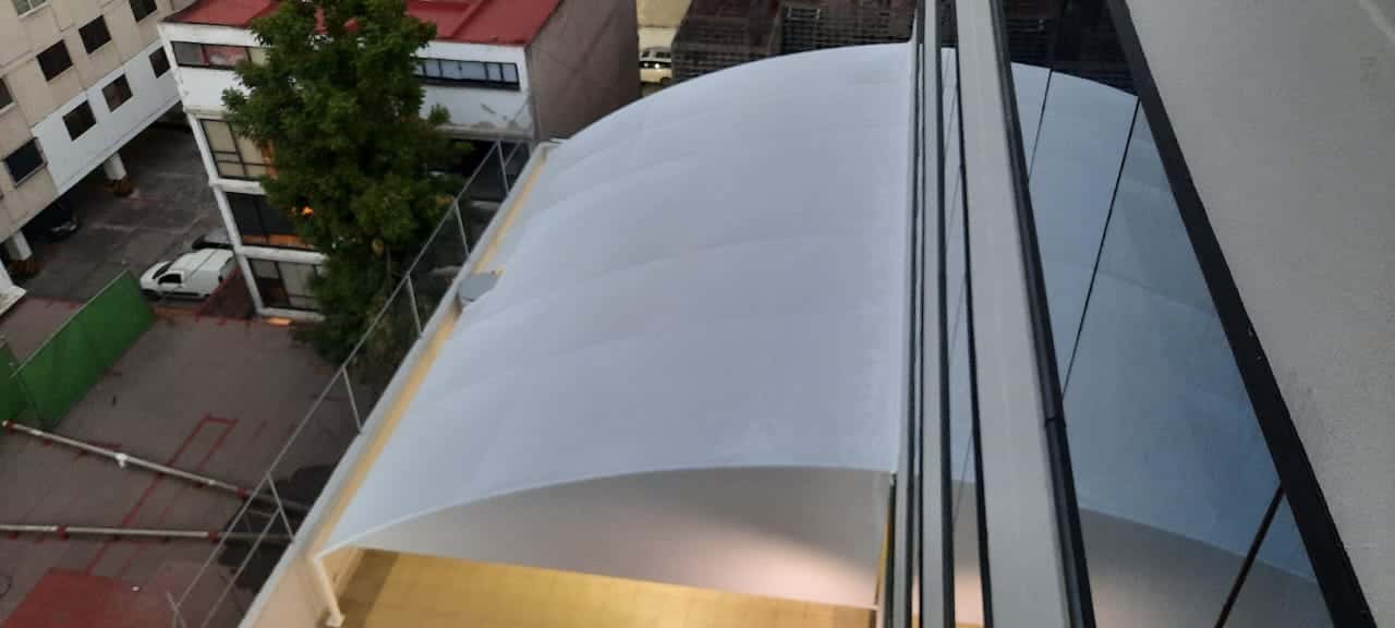 Espacio exterior protegido por la velaria, creando un ambiente formal.