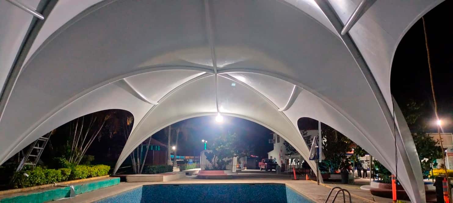 Zona de descanso con sombra junto a la alberca techada en Puebla.