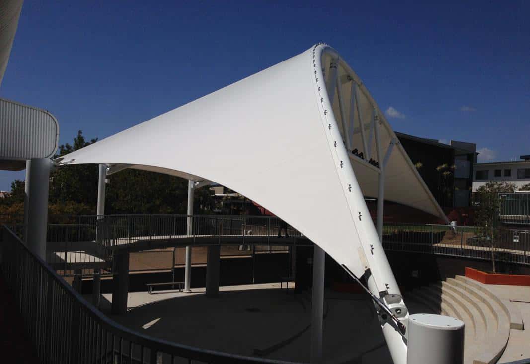 Público protegido del sol bajo la cubierta del foro para eventos.