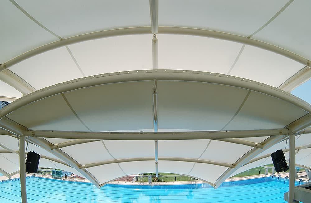 Moderno diseño de velaria de lona blanca cubriendo la terraza de un edificio.